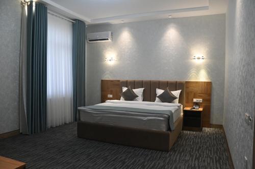 a bedroom with a large bed with white sheets and pillows at My Status Hotel in Tashkent