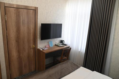 a room with a desk with a television and a door at My Status Hotel in Tashkent