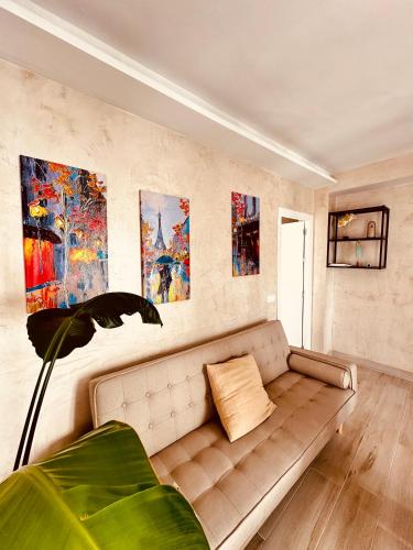 a living room with a couch and paintings on the wall at Cherry JACUZZI Apartment in Ronda