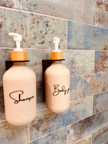 two bottles of soap sitting on a tile wall at Cherry JACUZZI Apartment in Ronda