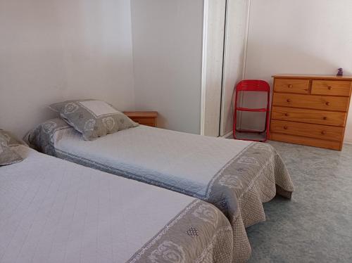 une chambre avec deux lits et une commode et une valise rouge dans l'établissement Villa 6 pers climatisee avec terrasse et Parking prive - V0270, à Vias