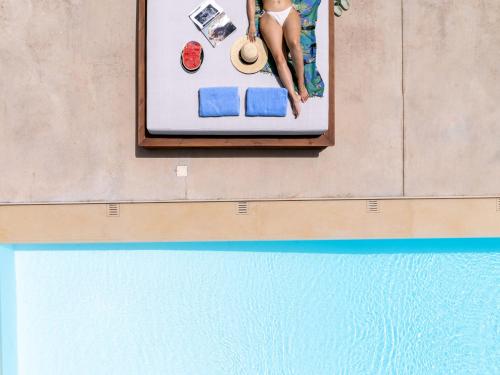 a woman in a bikini sitting on a towel next to a swimming pool at Villa Ellie - heated pool, playground, garden & BBQ! in Vederoi