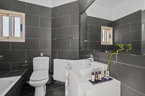 a bathroom with a white toilet and a sink at Harmonia Luxury Villa by Nomads in Peyia