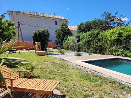 a backyard with a pool and a bench and a house at Gîte l'atelier de Phil et Delfe in Sainte-Cécile-les-Vignes