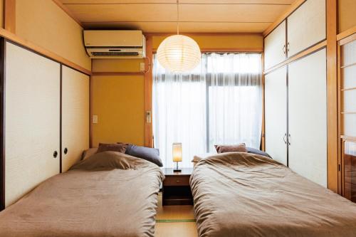 two beds in a room with a window at 彦宿Hikojyuku戸建て貸切宿 in Hikone