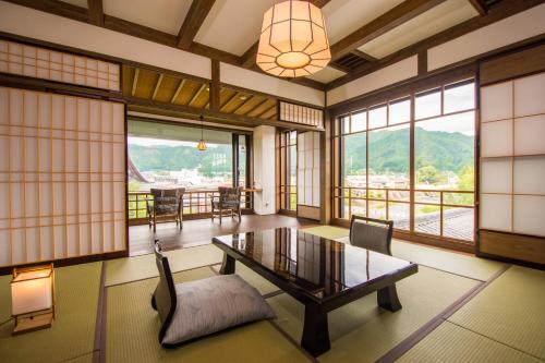 a living room with a table and chairs and windows at Yatsusankan in Hida