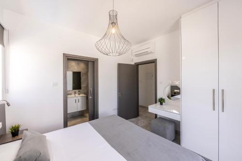 a white bedroom with a bed and a bathroom at Fig Tree Bay Residences 1 Lantiana Villa in Protaras
