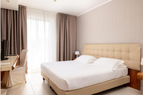 a bedroom with a large white bed and a desk at D'Aragona Lifestyle Hotel in Conversano