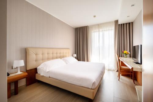 a bedroom with a bed and a desk and a television at D'Aragona Lifestyle Hotel in Conversano