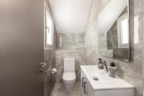 a bathroom with a sink and a toilet and a mirror at Fig Tree Bay Residences 1 Lantiana Villa in Protaras