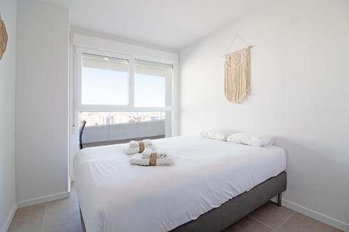 ein weißes Schlafzimmer mit einem Bett mit weißer Bettwäsche und einem Fenster in der Unterkunft Global Properties, Apartamento con vistas al mar en Canet in Canet d'en Berenguer