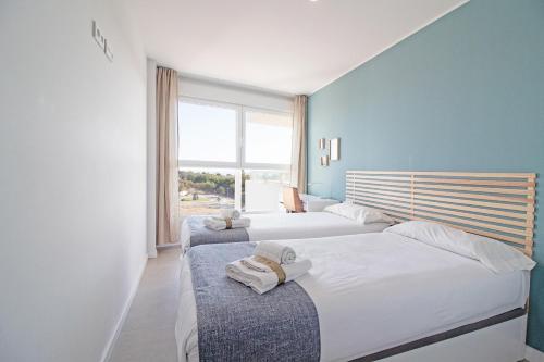 a bedroom with two beds and a window at Global Properties, Moderno apartamento con gran terraza y vistas al mar in Canet de Berenguer