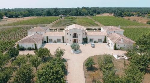 - une vue aérienne sur une grande maison dans un vignoble dans l'établissement La Tour Bélize du Château Saint-Laurent, à Saint-Laurent-de-Médoc