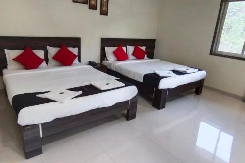 two beds in a room with red and white pillows at Jagdish Deluxe Hotel in Dapoli