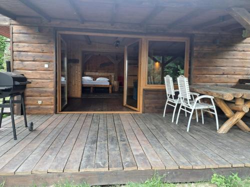 a wooden deck with chairs and a table and a bed at Siedlisko nad Jeziorem-Mazury in Mrągowo