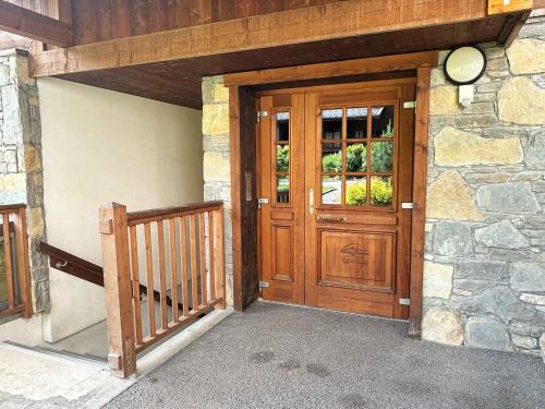 - une entrée pour une maison avec une porte en bois dans l'établissement Appartement de charme avec terrasse, piscine et parking, proche centre et arrêt ski-bus - FR-1-624-105, à Samoëns
