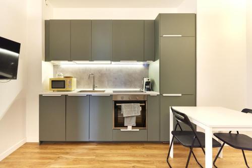 una cucina con armadi grigi, tavolo e lavandino di Nolo studio walking distance from Loreto e Corso Buenos Aires a Milano