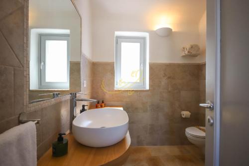 a bathroom with a tub and a toilet and two windows at TD Trulli Locobello Stylish & Cozy Trulli with Pool in Martina Franca