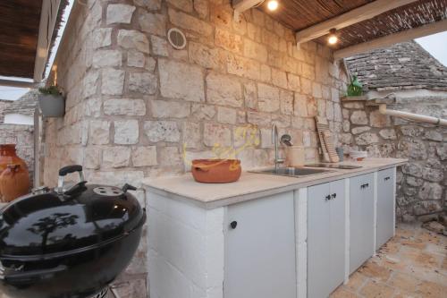 a kitchen with a sink and a stone wall at TD Trulli Locobello Stylish & Cozy Trulli with Pool in Martina Franca