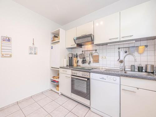 a kitchen with white appliances and white cabinets at Ferienwohnung Seebergweg in Maasholm-Bad