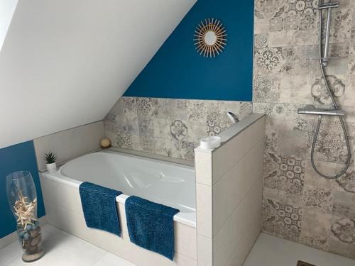 La salle de bains est pourvue d'une baignoire et d'une douche aux murs bleus. dans l'établissement Maison, à Baden