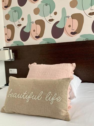 a bed with a brown pillow with a beautiful life wall at Ambassadeur Hotel - Cherbourg Port de Plaisance in Cherbourg en Cotentin