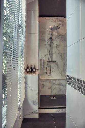 La salle de bains en marbre blanc est pourvue d'une douche. dans l'établissement Chic et décontracté centre de paris, à Paris