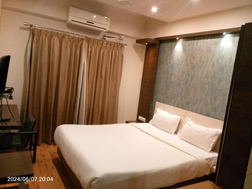 a bedroom with a large white bed and a window at Hotel Sandalwood Inn - Rooms and Spa in Bengaluru