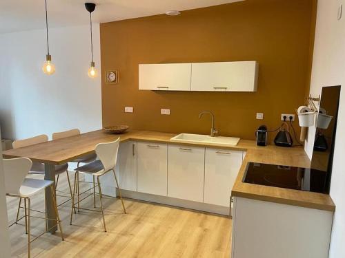 une cuisine avec des armoires blanches et une table avec des chaises dans l'établissement Guérande, appartement de charme Porte Saint-Michel, à Guérande