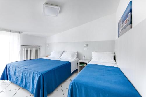 two beds in a room with blue sheets at Residence Diffuso Arcobaleno in Gabicce Mare