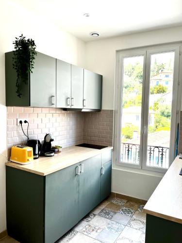 une cuisine avec des placards bleus et une fenêtre dans l'établissement Modern flat near sea and center, à Nice