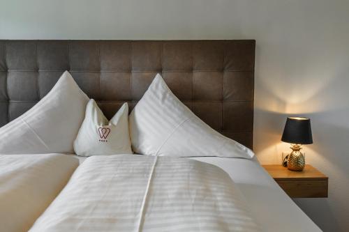 a bed with white sheets and pillows and a lamp at Hotel & Restaurant Wastlwirt in Sankt Michael im Lungau