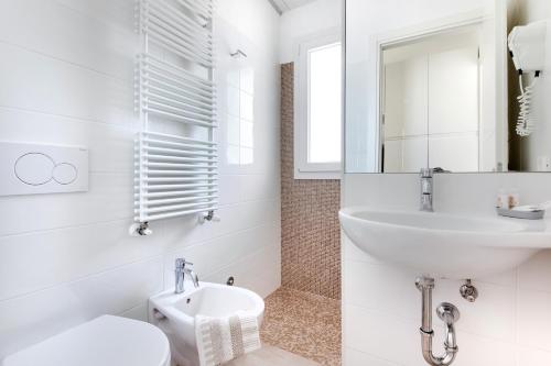 a white bathroom with a sink and a toilet at Residence Diffuso Arcobaleno in Gabicce Mare