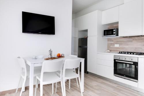 a white kitchen with a white table and chairs at Residence Diffuso Arcobaleno in Gabicce Mare
