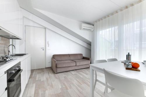 a white kitchen with a table and a couch at Residence Diffuso Arcobaleno in Gabicce Mare