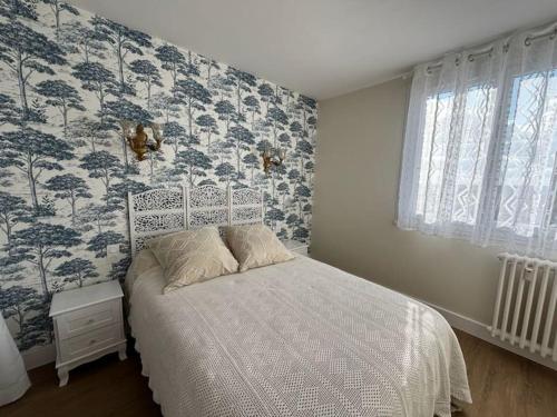 - une chambre dotée d'un lit avec du papier peint bleu et blanc dans l'établissement Les alouettes, à Aurillac