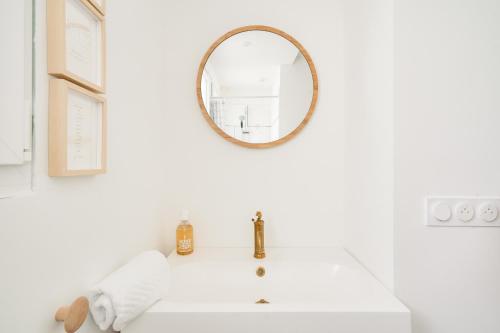 une salle de bain blanche avec un lavabo et un miroir dans l'établissement Jolie maison pour 4 - 300m plage et etang, à l'Île-Tudy