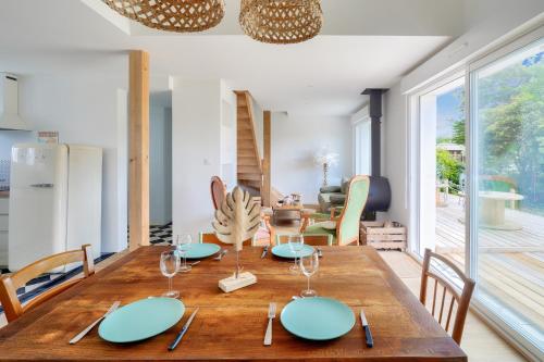 - une salle à manger avec une table en bois, des assiettes et des verres à vin dans l'établissement Jolie maison pour 4 - 300m plage et etang, à l'Île-Tudy