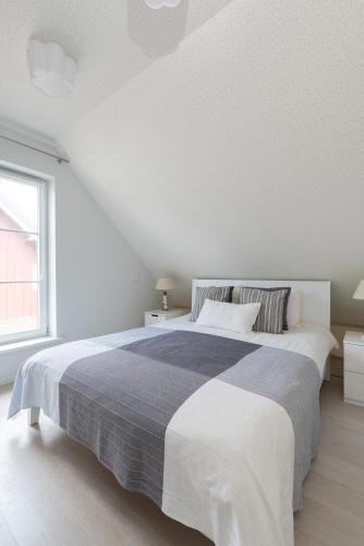 a white bedroom with a large bed and a window at Egidijaus Vila in Nida