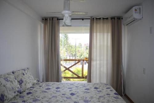 a bedroom with a bed and a large window at Paraíso dos Corais in Guarajuba