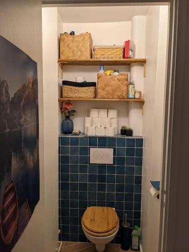 La salle de bains est pourvue de toilettes et d'un mur carrelé bleu. dans l'établissement Charmant T5 en pleine nature à Viroflay-Versailles, à Viroflay