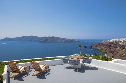 a patio with a table and chairs overlooking the water at IKIES Santorini in Oia