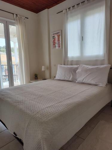 a bedroom with a large white bed with a window at Evi's house in Nikiana