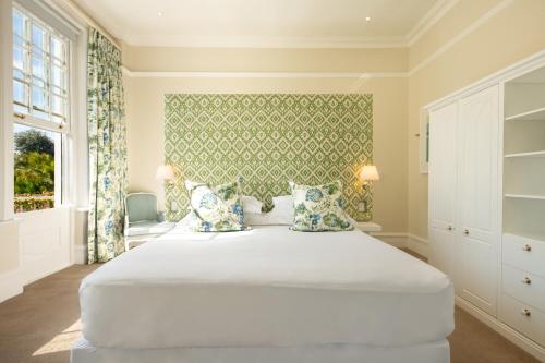 a bedroom with a large white bed with pillows at The Cellars-Hohenort in Cape Town