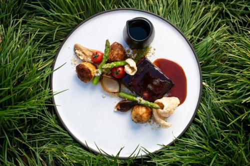 a white plate with food on top of green grass at The Cellars-Hohenort in Cape Town