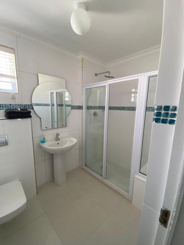 a white bathroom with a shower and a sink at Bed and Breakfast Villa Livadia in Cape Town