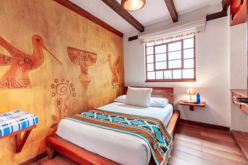 a bedroom with a bed and a wall with paintings at Acoma in Otavalo