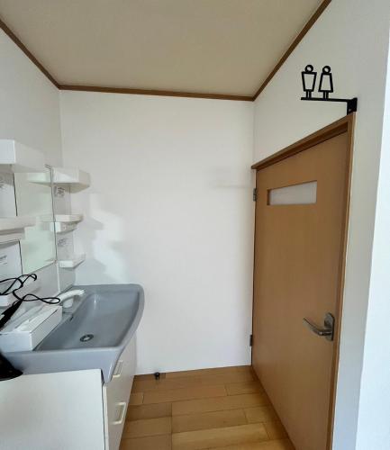 a bathroom with a sink and a door at Jin in Oyodo