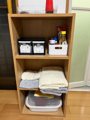 a wooden shelf with towels and other items in a kitchen at Jin in Oyodo