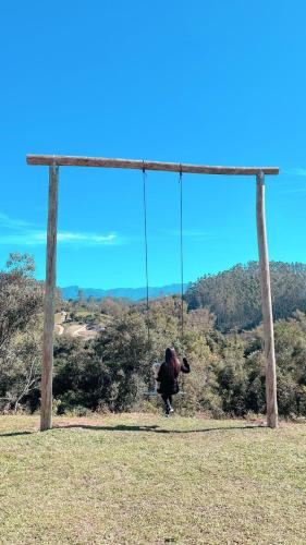 a person on a swing in a field at CABANAS BELVEDERE- SERRA DO RIO Do RASTRO in Louro Müller